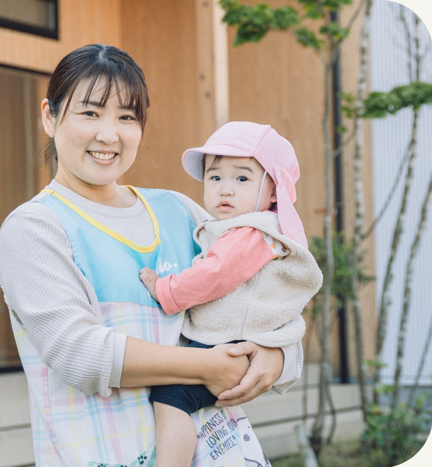 赤ちゃんを抱っこしてほほえむ保育士